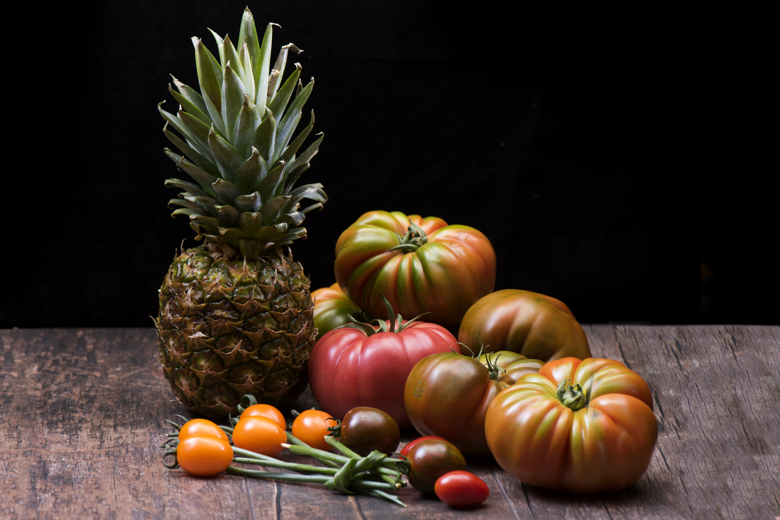 Sebze fotoğrafı: ananas, domates çeşitleri ve sebzelerle tahta zemin kompozisyonu